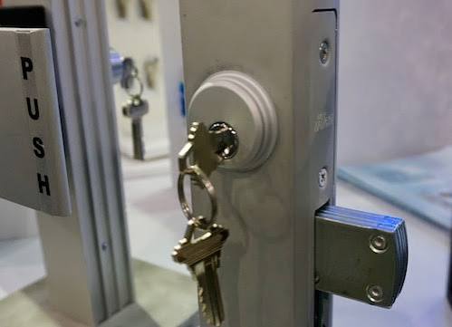 A storefront door mortise lock with keys beside a PUSH plate, commercial locksmith service