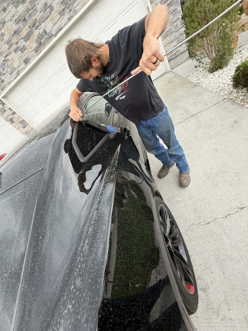David opening a locked car with a rod tool in a driveway